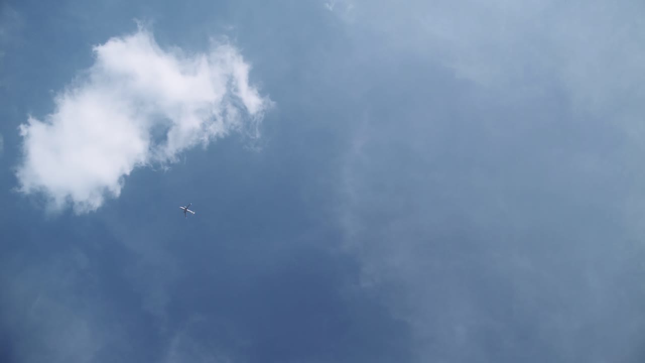 화면 오른쪽 아래에서 왼쪽 위 모서리까지 깊고 푸른 맑은 하늘을 가로질러 천천히 날아가는 비행기의 꾸준한 샷