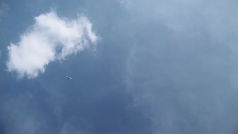 steady shot of airplane slowly flying across a deep blue sunny sky from the bottom right to the top left corner of the screen