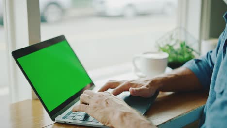 hombre trabajando en la pantalla verde de la computadora portátil