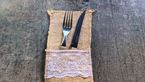 Rustic fork and knife on lace burlap against weathered wood table