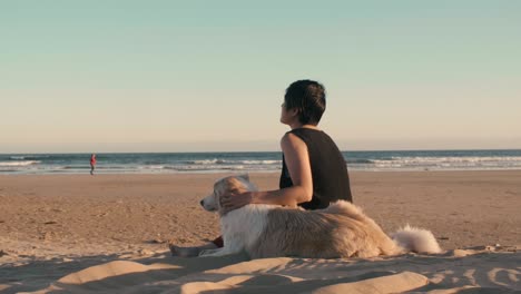 woman at beach with pet dog, watching the waves