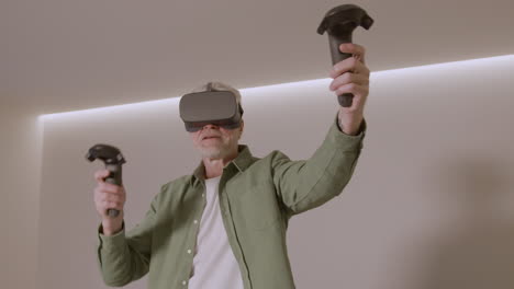 senior man playing at home with virtual reality goggles headset