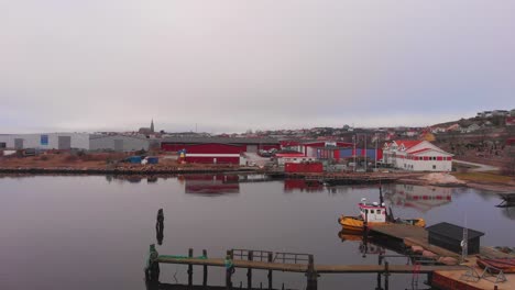 Vista-De-Pájaro-De-Una-Ciudad-Tranquila-Y-Hermosa-En-Lysekil,-Suecia-Con-Barco-Turístico-Y-Casas-únicas-Que-Rodean-El-Mar-En-Calma---Toma-Aérea