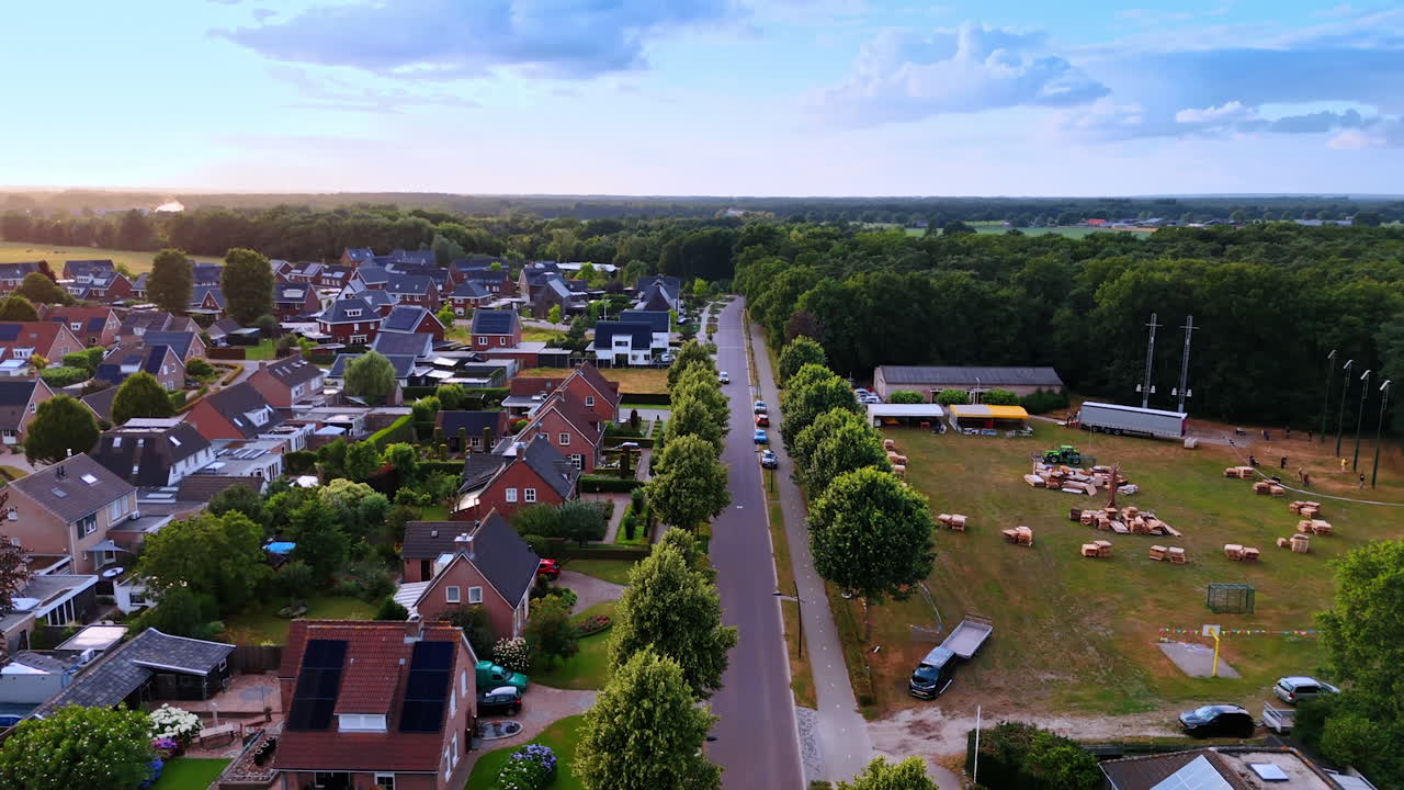 Peaceful suburban neighborhood at dusk. A quiet suburban area features houses lining a tree-lined street at sunset with green fields nearby