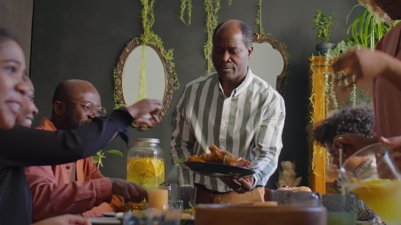 African American Man Taking Care of Guests at Family Dinner