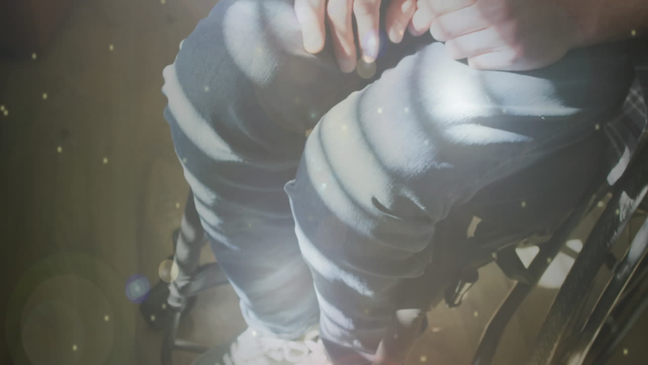 체어에 앉아 있는 장애인 백인 남성 위에 빛의 반점이 그려져 있습니다.