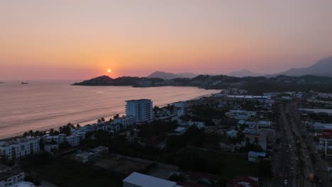 Aerial-View-Of-Sun-Setting-Behind-The-Santiago-Peninsula-At-Dusk-From-Manzanillo,-Colima,-Mexico