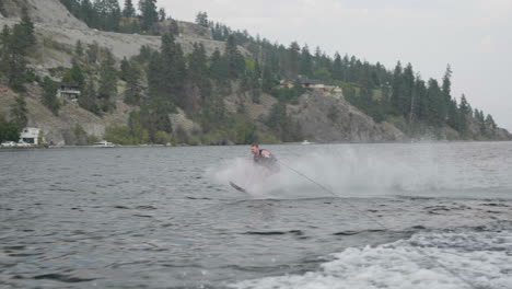 man water skiing behind boat on mountain lake with big water splash