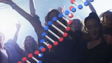 dna structure spinning against group of people dancing together at a concert