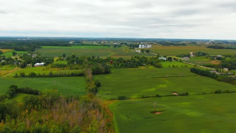 aerial establishing shot of rural wisconsin farmland with fields, trees, and farms