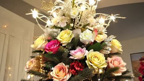 decorator adding final touches to a beautifully adorned christmas tree with flowers and colorful ornaments