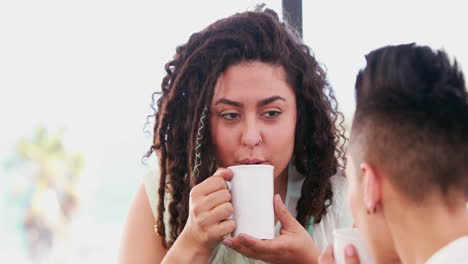 smiling lesbian couple drinking coffee together