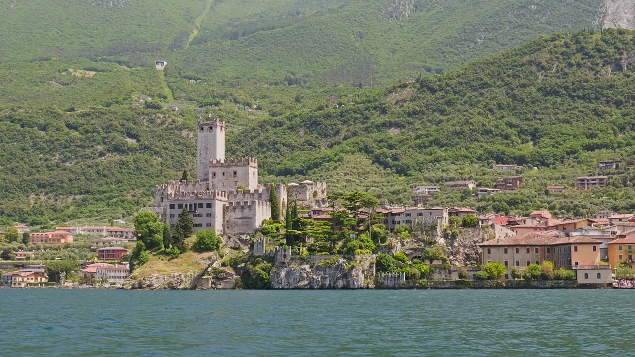 Establishing shot Scaliger castle Malcesine from Lake Garda boat cruise