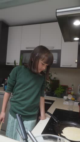 young girl cooking pancakes in a kitchen