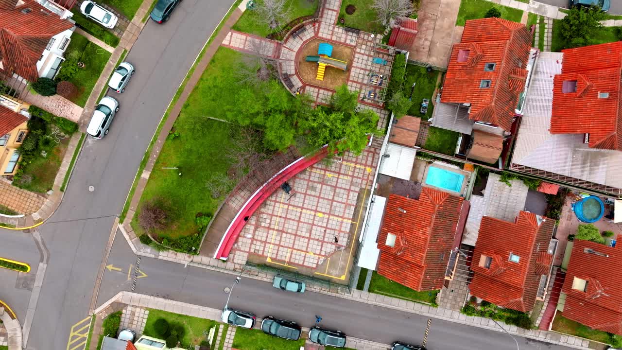 antena de arriba hacia abajo en dolly de un hombre jugando baloncesto en su patio, rodeado de casas de clase media con tejas rojas, quilpue, chile