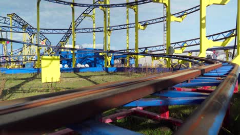 Rail-track-of-a-closed-roller-coaster,-in-an-abandoned-funfair-during-Coronavirus-Covid-19-pandemic-lockdown,-empty-scenery-in-an-amusement-park