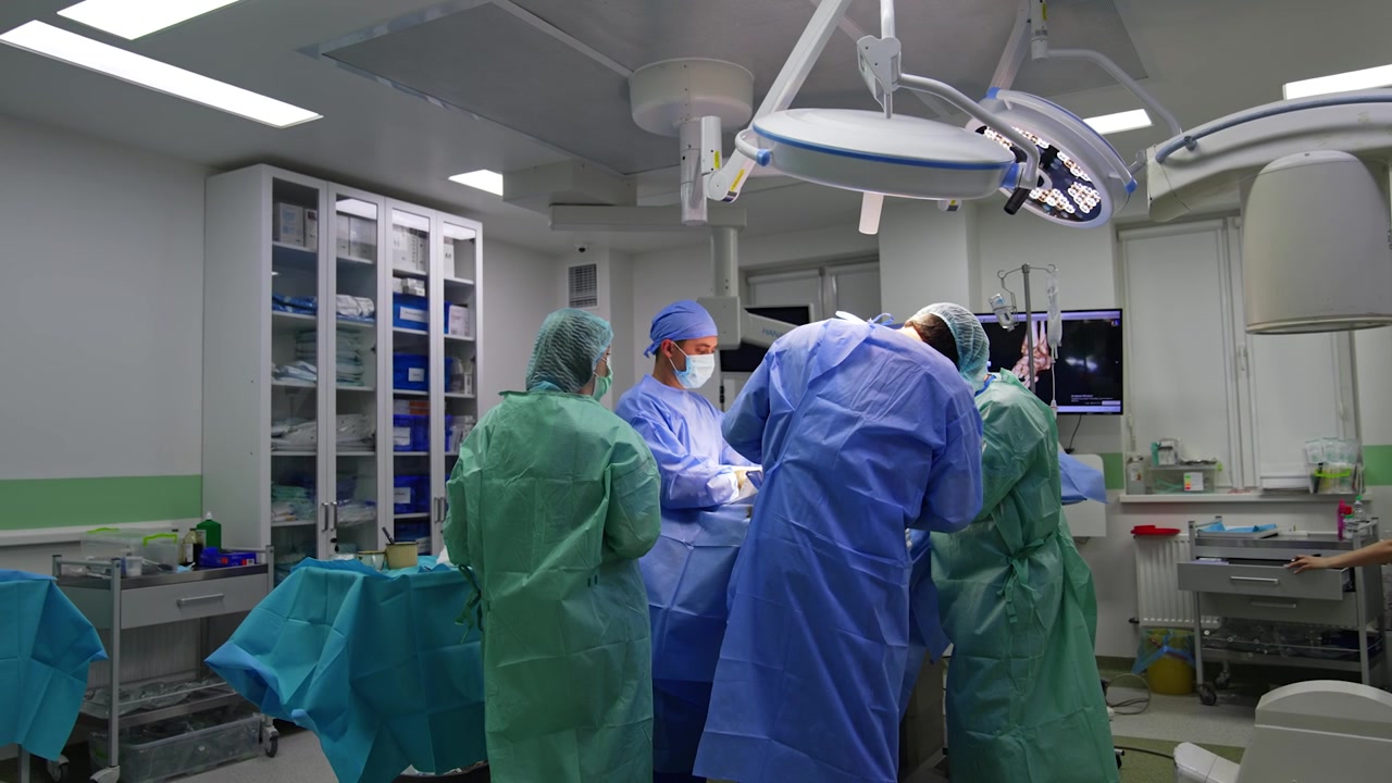 Two surgeons, assistant and scrub nurse surrounding the operational table. Surgical team carrying out the trauma surgery.