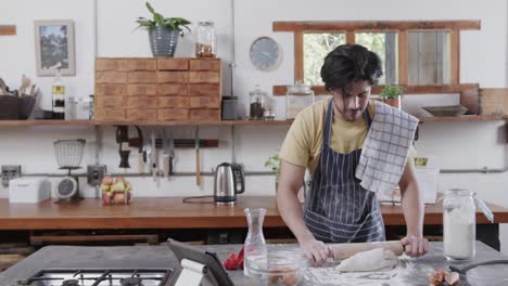 caucasian man preparing bread dough using tablet in kitchen, slow motion