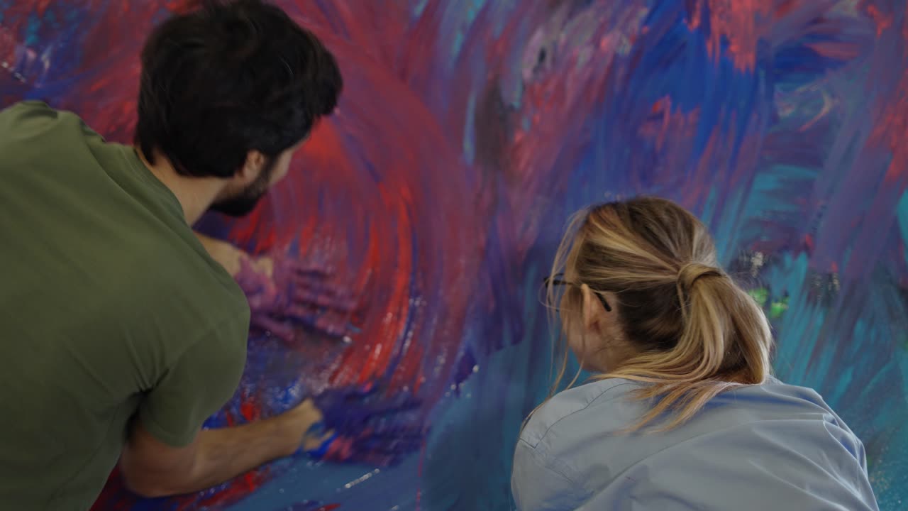 pareja de enamorados tomados de la mano y manchando pinturas coloridas en el lienzo