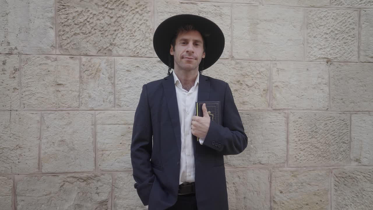 hombre judío ortodoxo de pie frente a una pared de piedra