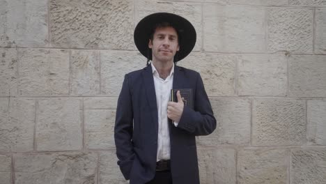 hombre judío ortodoxo de pie frente a una pared de piedra