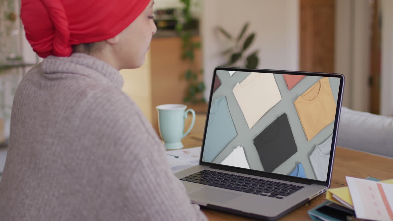 mujer biracial usando portátil, compras en línea de ropa, cámara lenta