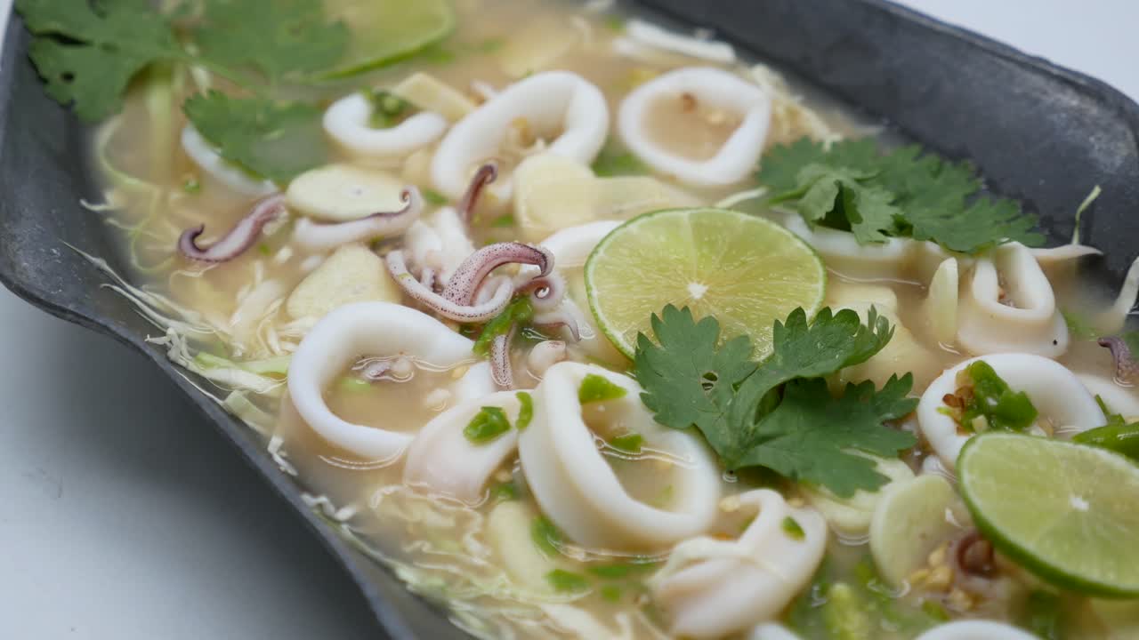 imágenes de primer plano de calamares agridulces en sopa de chile, ajo y lima