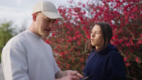 caucasian couple check smartphone for directions near chinese quince shrub