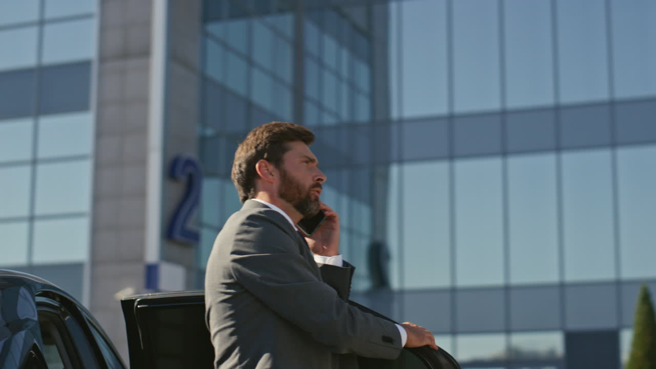 hombre de negocios adinerado llamando al teléfono móvil saliendo de un coche caro de cerca