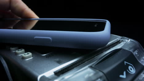 Unrecognizable woman making payment through smartphone using NFC technology