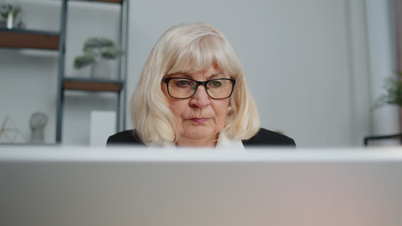 mujer de negocios senior freelance usando computadora portátil se sienta en el lugar de trabajo escribiendo navegando en la oficina