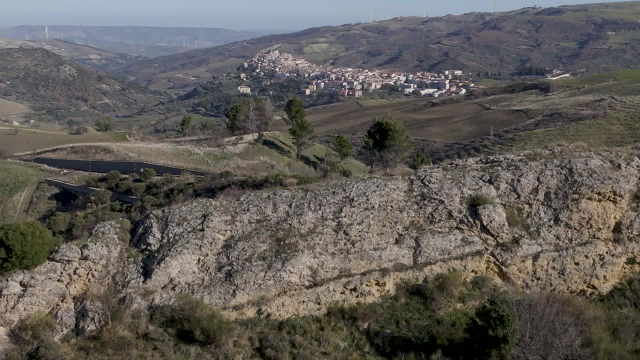 Matera, Italia, che si rivela dietro una catena montuosa con riprese aeree da drone in ascesa