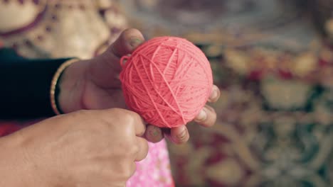 Nahaufnahme-Der-Hände-Einer-Frau,-Die-Langsam-Rote-Wolle-Zu-Einem-Ball-Rollt