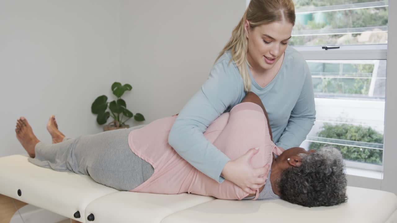Caucasian female physiotherapist massaging senior woman, copy space, slow motion