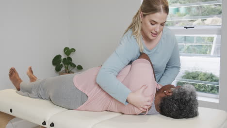 caucasian female physiotherapist massaging senior woman, copy space, slow motion