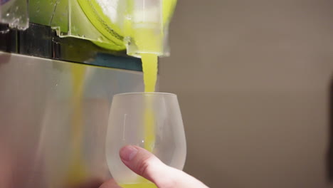 close up of green frozen slushie being served from machine into glass, 4k slow motion