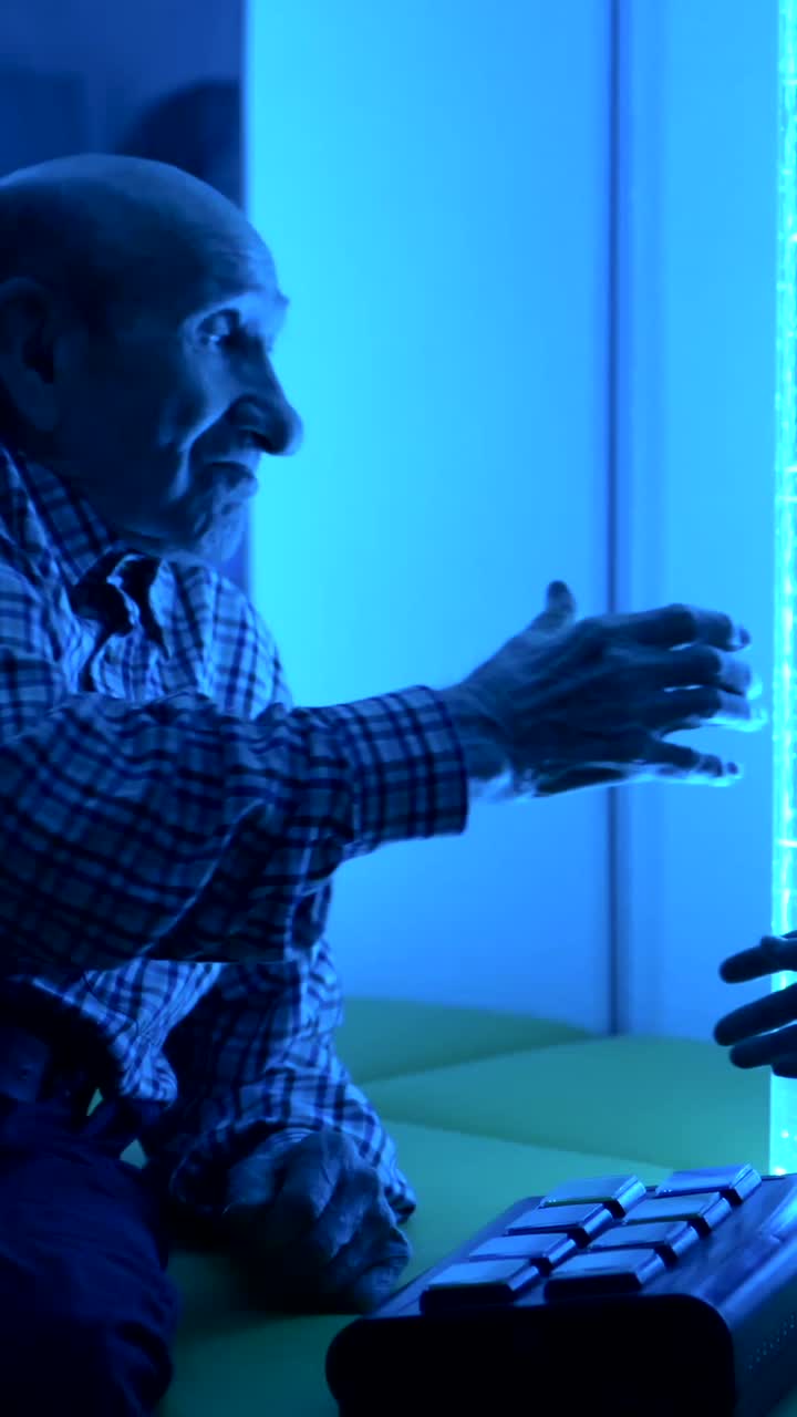 Elderly Man Interacting with Bubble Tube in Sensory Room