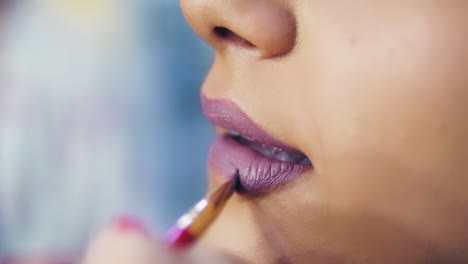 vista de cerca de un maquillador profesional que aplica pintalabios en los labios de la modelo que trabaja en la industria de la moda de belleza 1