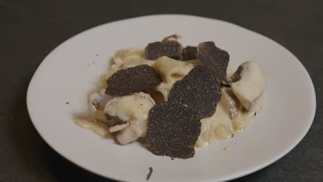Delicate-shavings-of-truffle-fall-onto-a-plate-of-creamy-pasta,-adding-an-exquisite-touch-to-the-dish