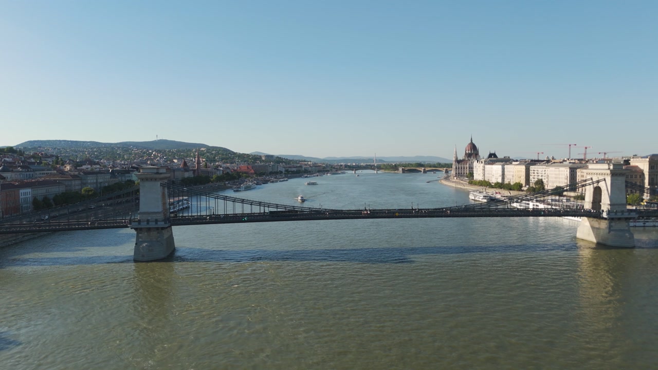 Smooth aerial reverse across the Danube exposing Budapest’s famous Széchenyi Chain Bridge connecting Buda and Pest