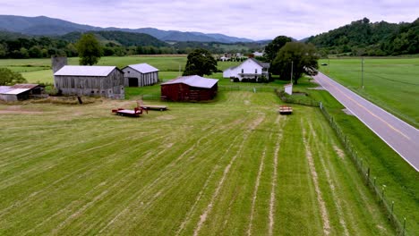 car along roadway in farm country with farmhouse in foreground aerial near mountain city tennessee