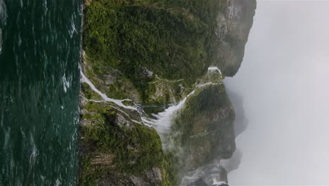 vertical of new zealand waterfalls in milford sound during a windy hail storm rainy season