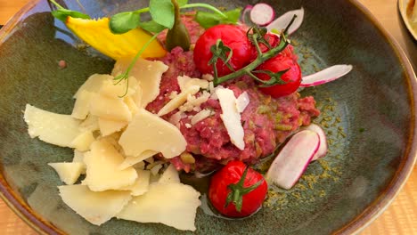 Delicioso-Tartar-De-Carne-Con-Queso-Parmesano,-Tomates-Cherry-Y-Capres-En-Un-Plato,-Toma-De-4k