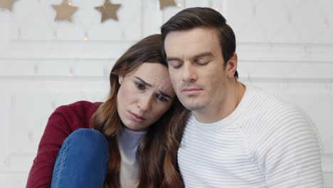 Portrait-of-sad-couple-watching-video-in-living-room.