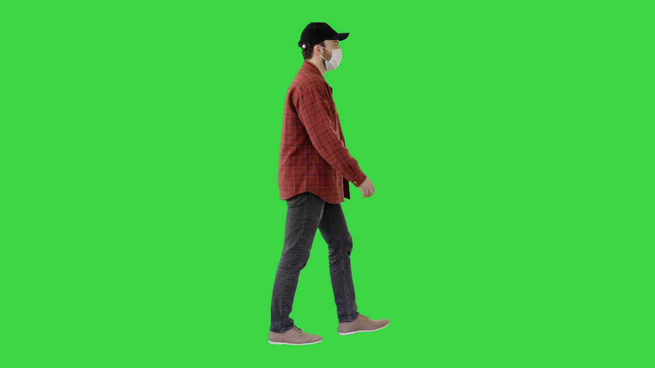 모자와 의료 마스크를 입은 미국 농부가 녹색 스크린, 크로마 키에서 걸어가고 있습니다.