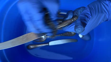 washing silverware in a blue bowl