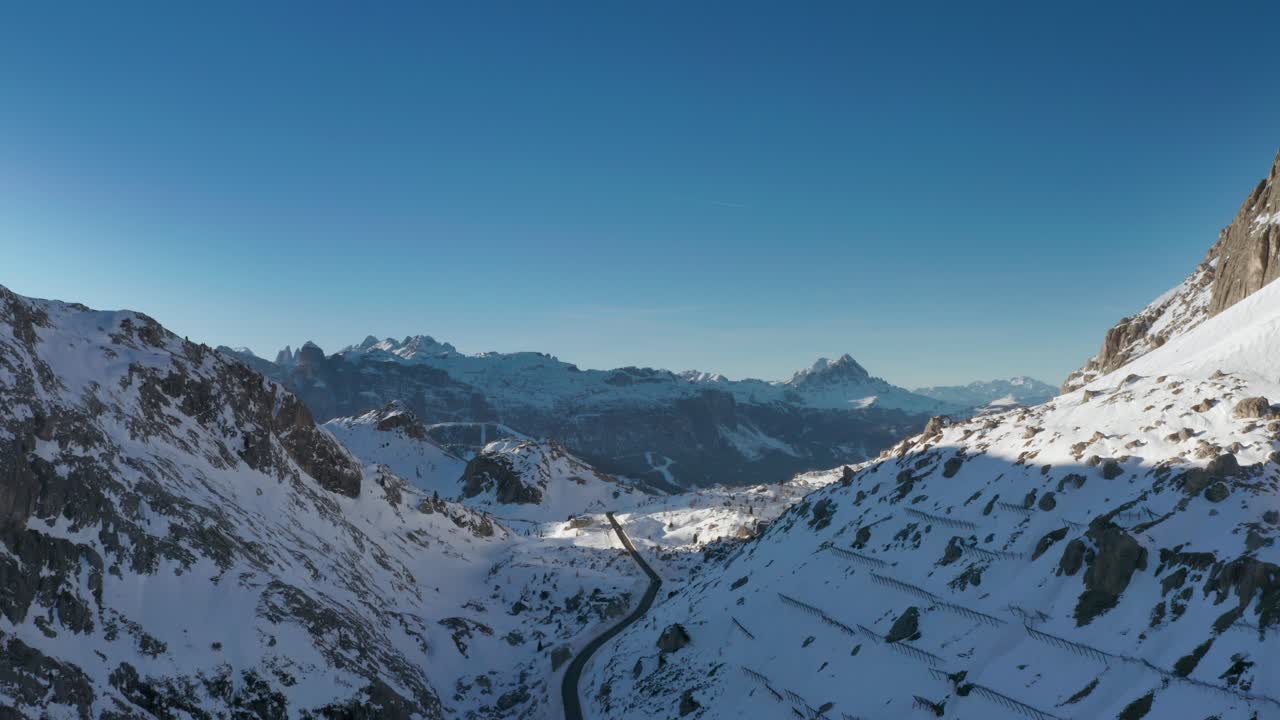 un camino estrecho que serpentea entre los picos montañosos cubiertos de nieve que conducen al passo falzarego en los dolomitas italianos