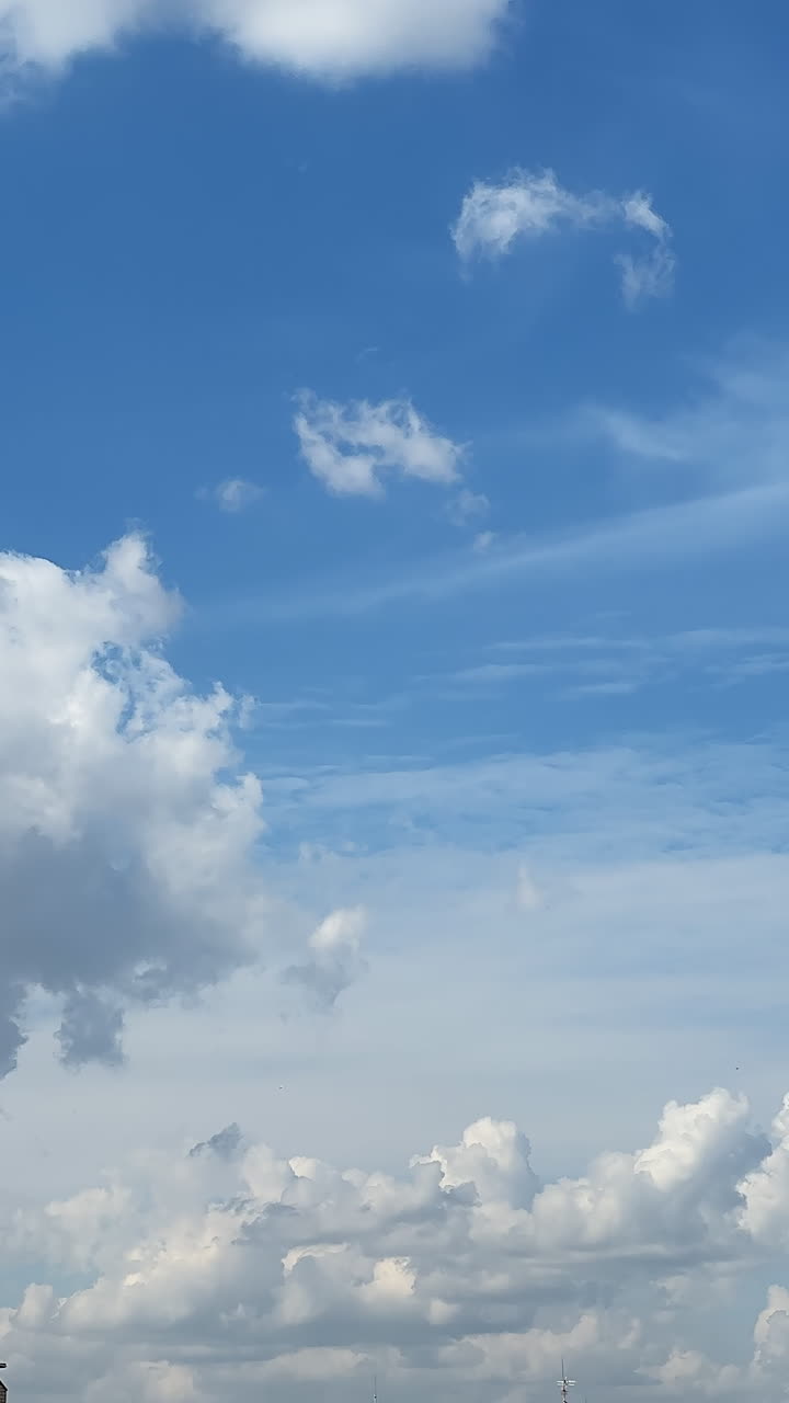 Fluffy white clouds transform in the blue sky. Beautiful drone footage in the sky among the changing cloudscape. Vertical video.