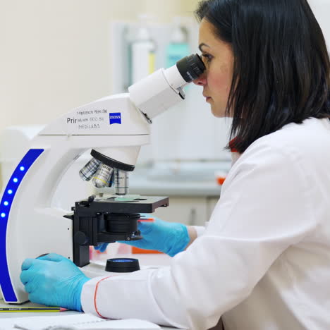 young woman researcher works with contemporary microscope. laboratory worker looking through the microscope. lab industry concept.