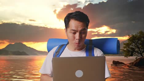 close up of asian male hiker with mountaineering backpack looking at a laptop and saying wow at a lake